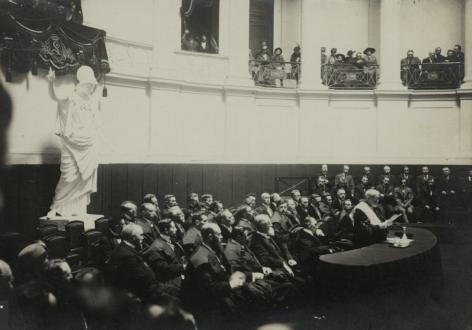 Rector Peter Hoffmann speecht in de Aula op de openingszitting van de Vlaamse Hogeschool op 24 oktober 1916. Op de achtergrond kijkt Minerva toe  (Collectie Universiteitsbibliotheek Gent)