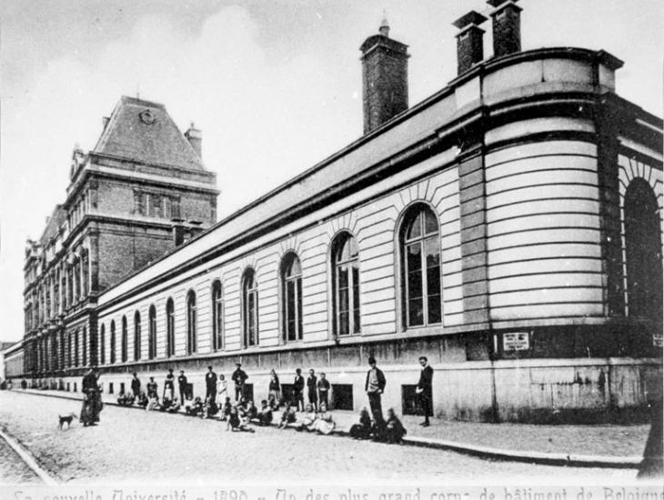 Het &#039;Instituut van de Wetenschappen&#039; in de Rozierstraat rond 1900. Ook voor de bouw van de 2de verdieping &#039;één van de grootste gebouwen van België&#039;. Op de voorgrond de buurtbewoners van de arbeiderswijk (Collectie Universiteitsarchief Gent).